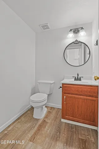 a bathroom with a toilet sink vanity granite and mirror