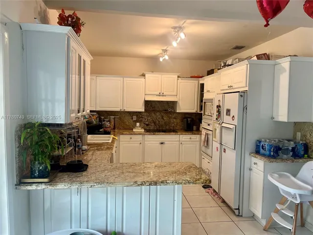 a kitchen with stainless steel appliances kitchen island granite countertop a refrigerator and a sink