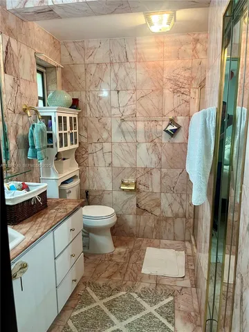 a bathroom with a granite countertop toilet a sink and shower