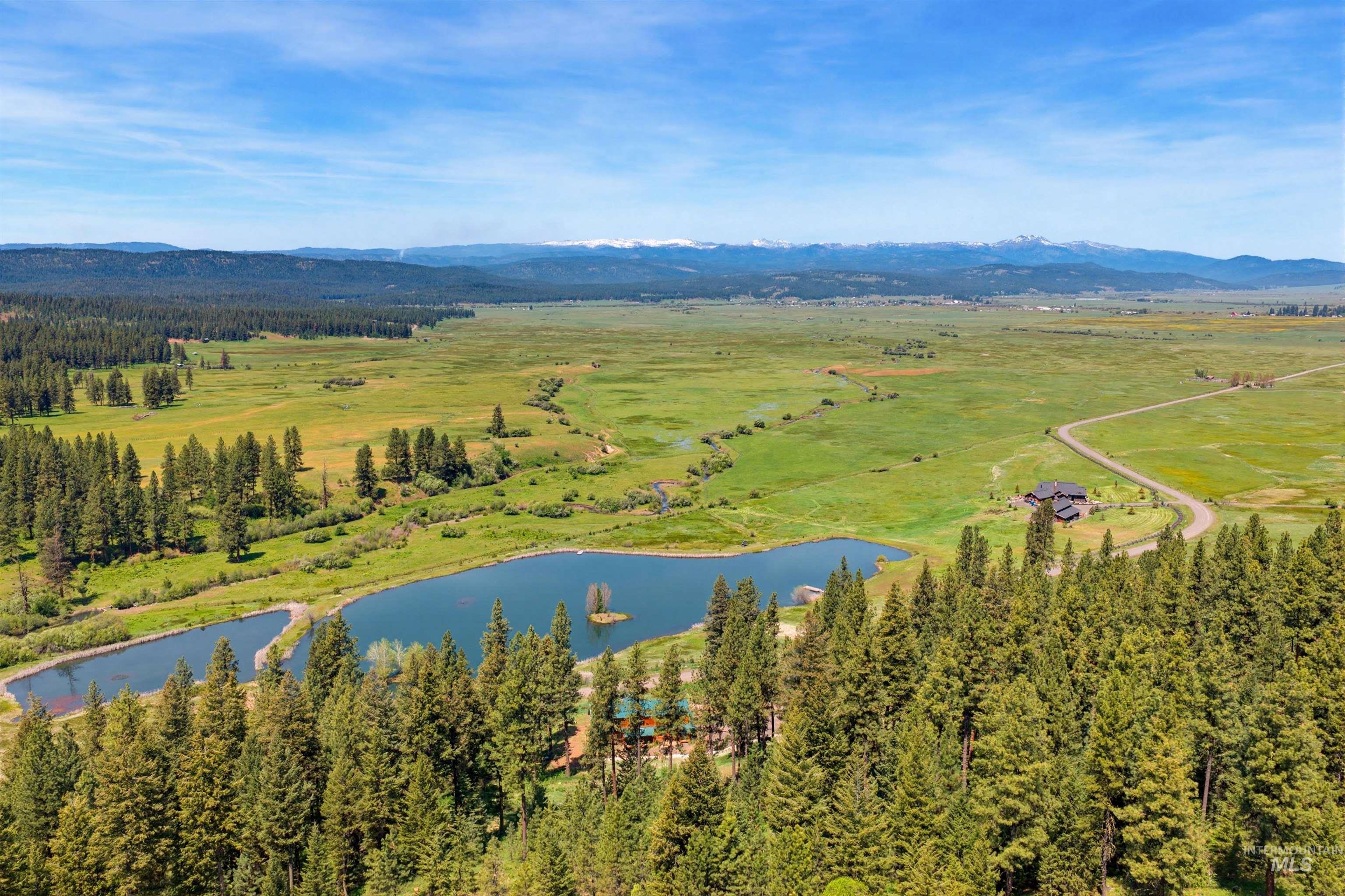 3322 Big Creek Road New Meadows, ID 83654 - Photo 14 of 50 Expansive natural landscape featuring two private ponds, mature evergreen trees, a winding dirt road, and a distant mountain range