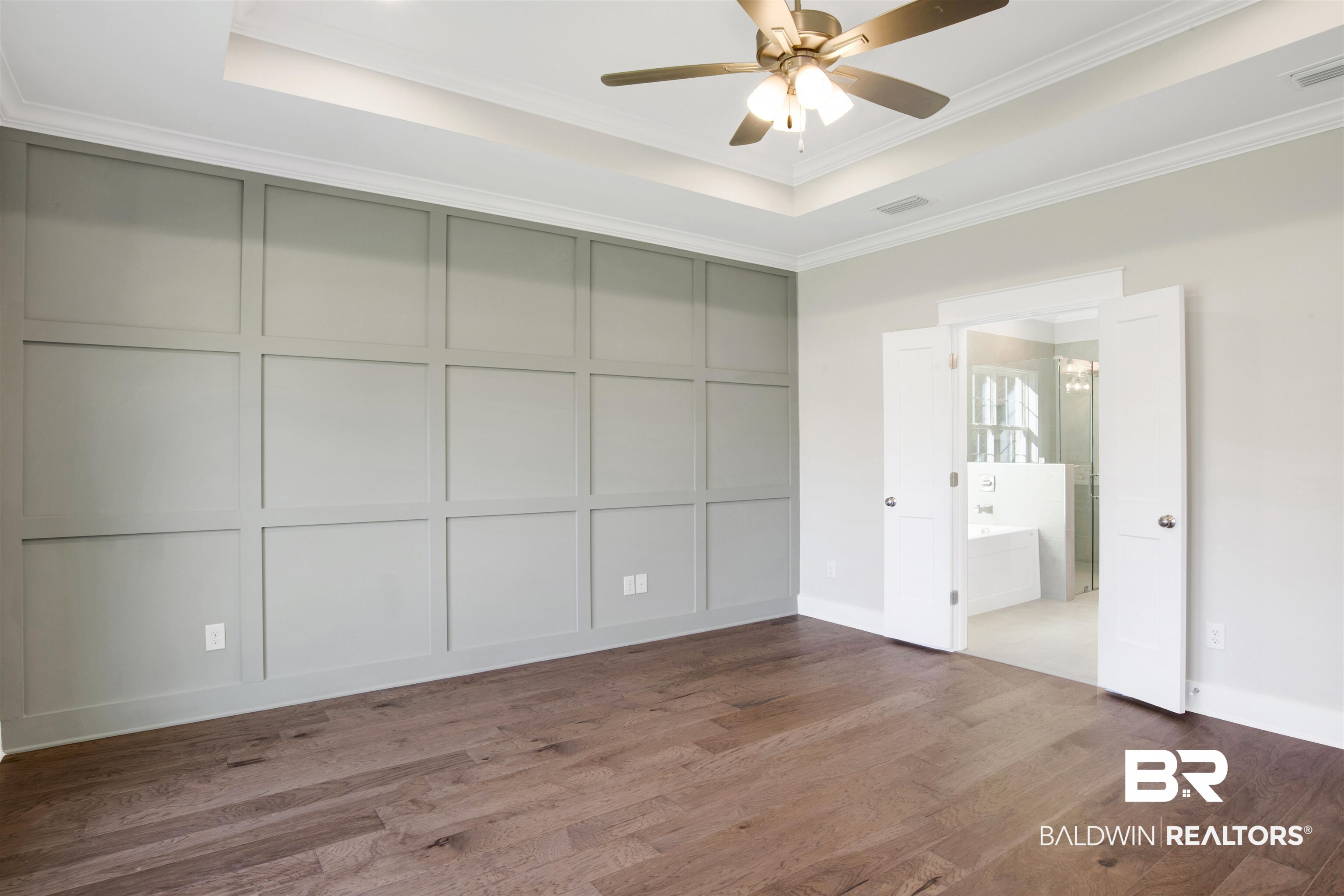 9687 Widgeon Court Daphne, AL 36526 - Photo 18 of 40 Unfurnished bedroom with ensuite bathroom, ceiling fan with notable chandelier, ornamental molding, a tray ceiling, and wood-type flooring