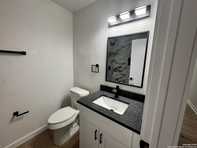a bathroom with a granite countertop sink toilet and a mirror