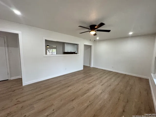 a view of a big room with wooden floor and a ceiling fan
