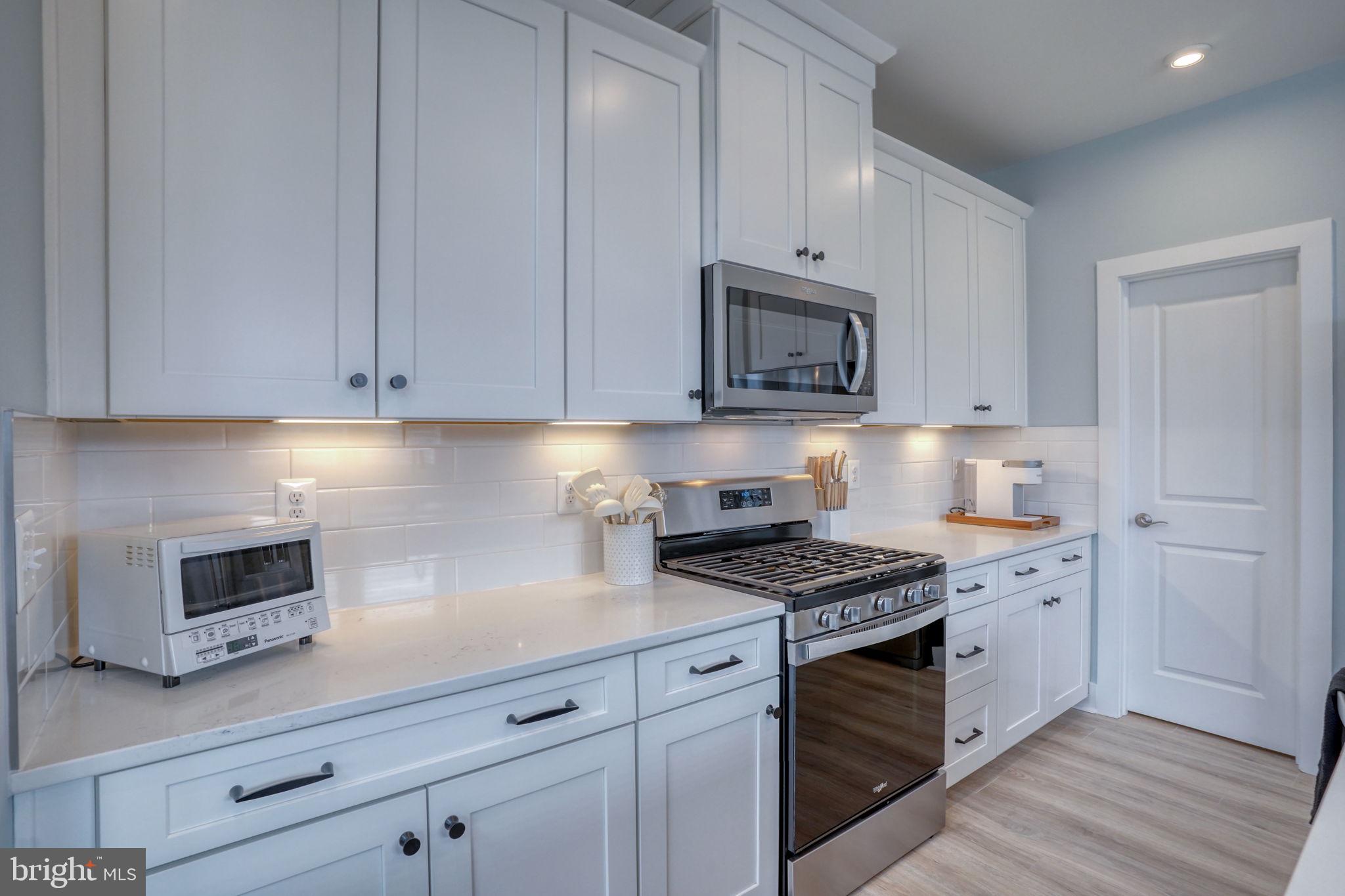 266 Exeter Street Ocean View, DE 19970 - Photo 11 of 62 a kitchen with granite countertop white cabinets stove top oven and microwave
