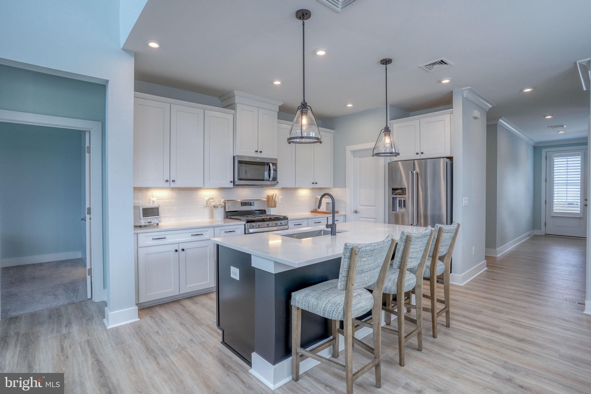 266 Exeter Street Ocean View, DE 19970 - Photo 5 of 62 a kitchen with stainless steel appliances kitchen island granite countertop a wooden floor and white cabinets