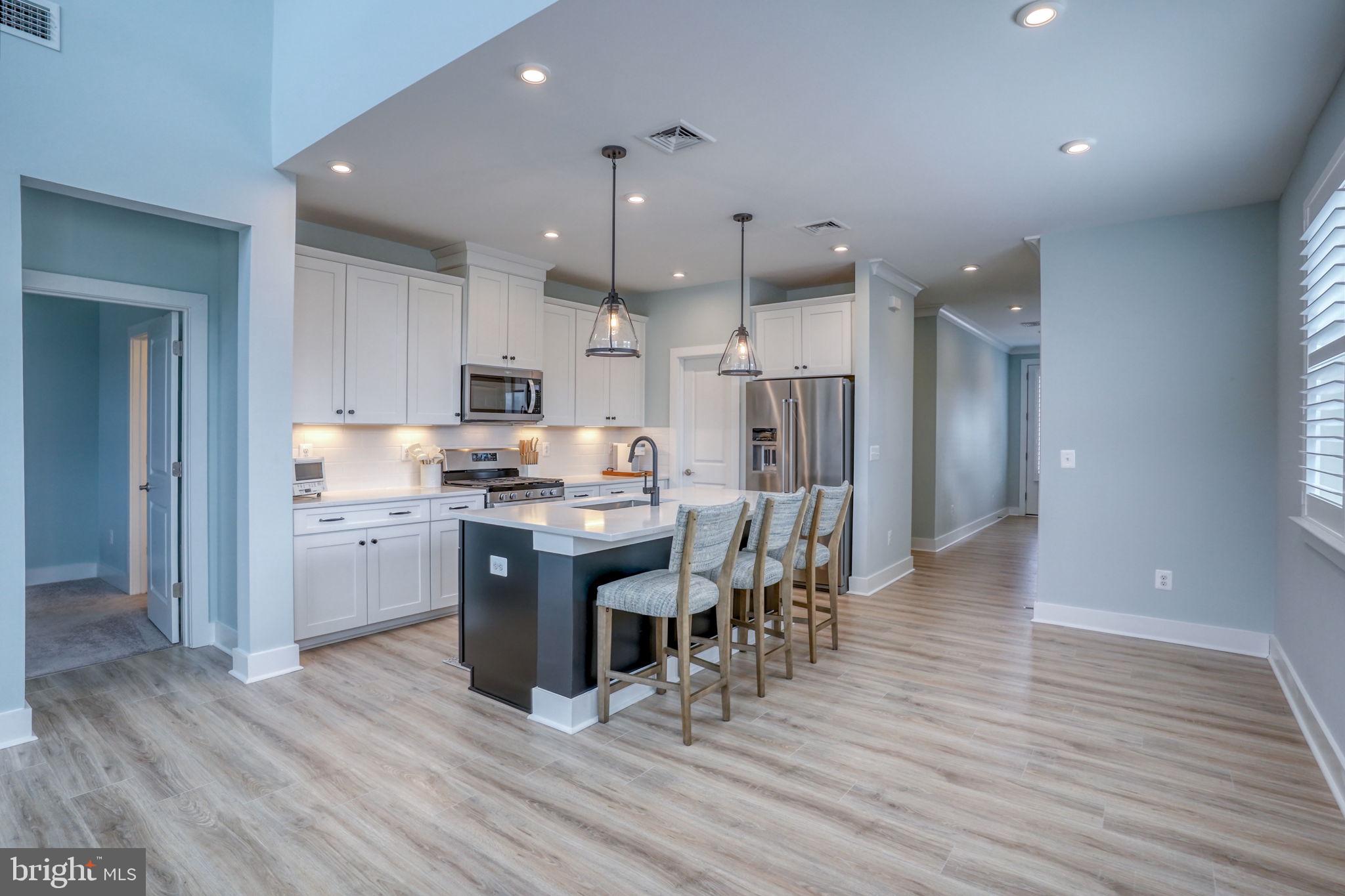 266 Exeter Street Ocean View, DE 19970 - Photo 8 of 62 a kitchen with stainless steel appliances kitchen island granite countertop a refrigerator a stove a sink and a dining table with wooden floor