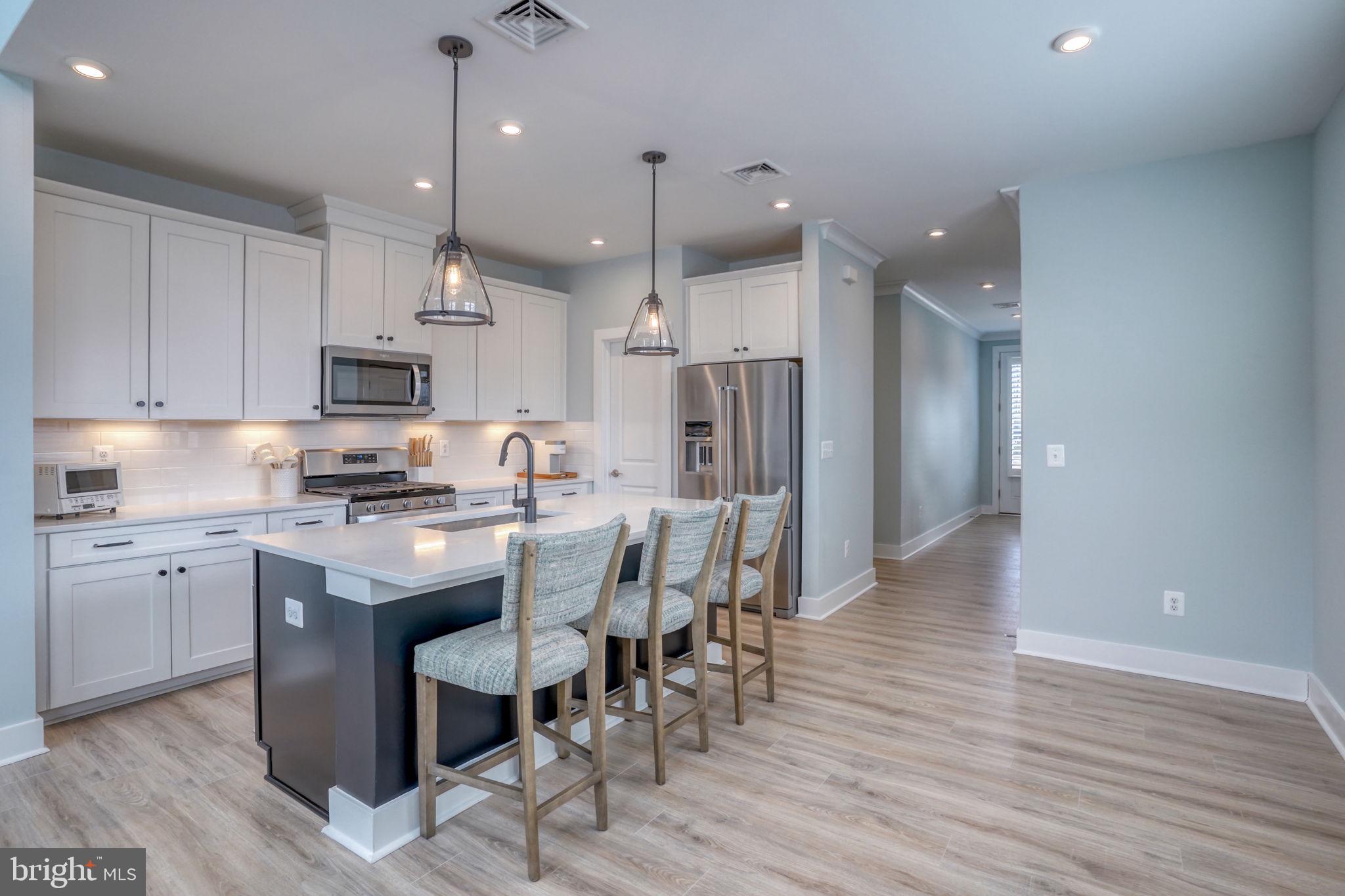 266 Exeter Street Ocean View, DE 19970 - Photo 9 of 62 a kitchen with stainless steel appliances granite countertop a table chairs refrigerator and microwave