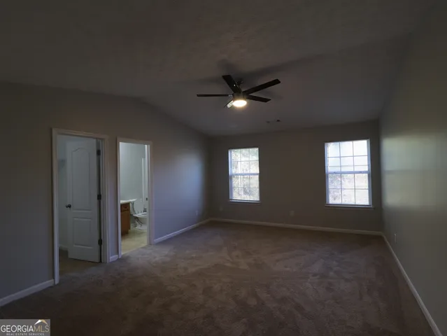 an empty room with windows and a ceiling fan