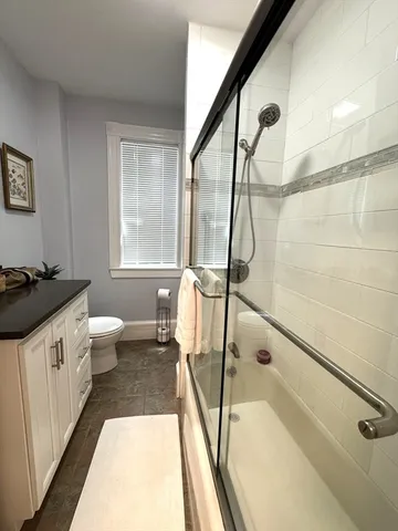 a bathroom with a sink a toilet a window and a shower