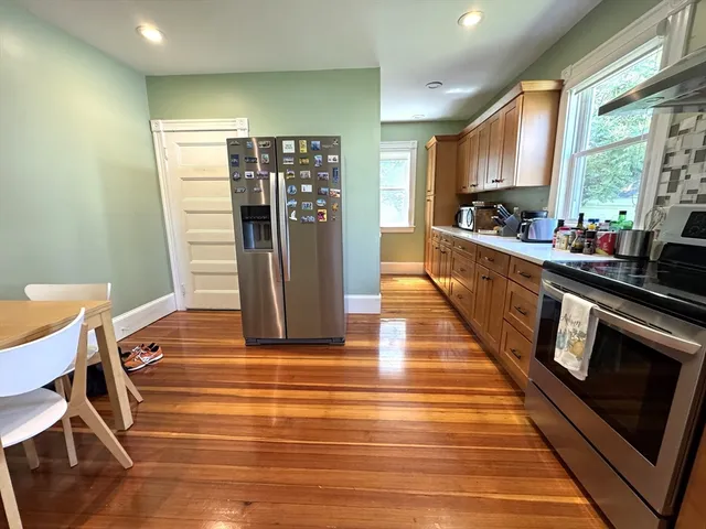 a view of a kitchen with kitchen island wooden floor center island and stainless steel appliances