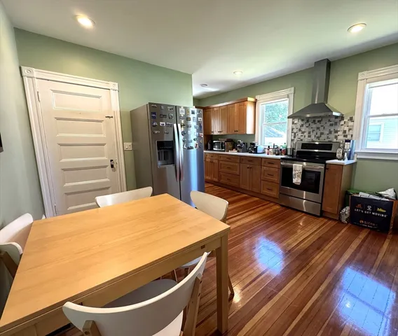 a kitchen with stainless steel appliances a stove a refrigerator and a sink with wooden floor