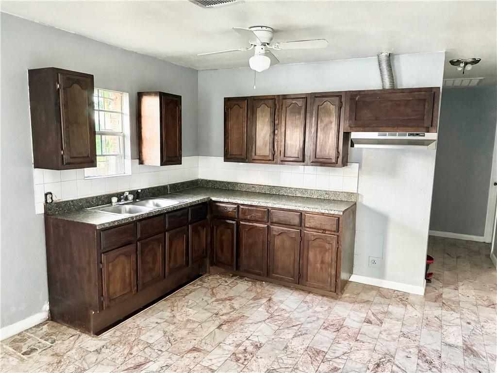 204 Ramon Private Road Mission, TX 78572 - Photo 5 of 11 Kitchen featuring wood cabinetry, a double basin sink, and a white tile backsplash