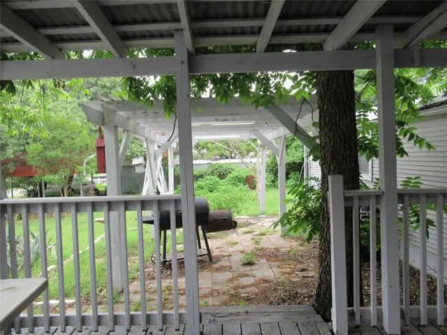a porch with a table and chairs next to a yard