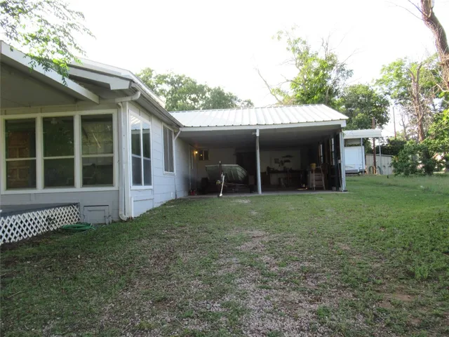 a view of a house with a yard and a large tree