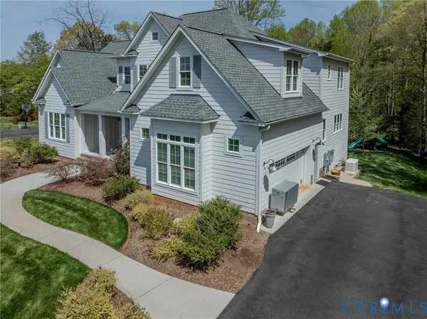 an aerial view of a residential houses with outdoor space and trees all around
