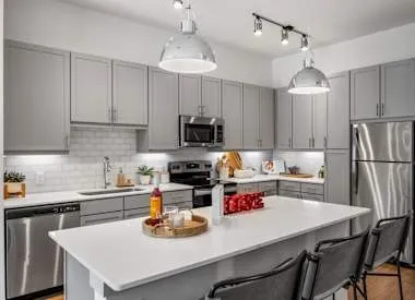 a kitchen with a stove a sink dishwasher a dining table and chairs with wooden floor