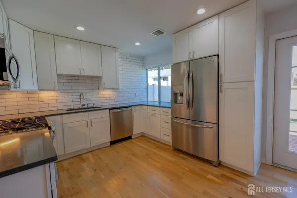 a kitchen with granite countertop stainless steel appliances a refrigerator a sink and cabinets