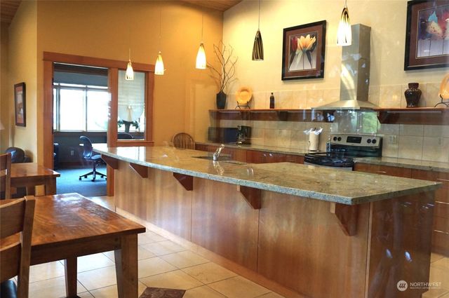 a room with kitchen island granite countertop a sink chairs and chandelier