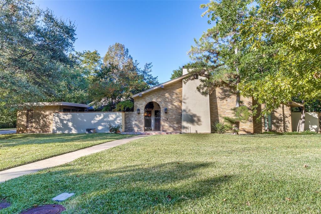 On an oversized .43 acre corner lot, with a deep grassy front lawn and wide side yard, surrounded by gorgeous leafy trees, the sidewalk leads you to an iron gate & covered entry, to a lovely Santa Fe style courtyard with trees, a patio and beautiful fountain.