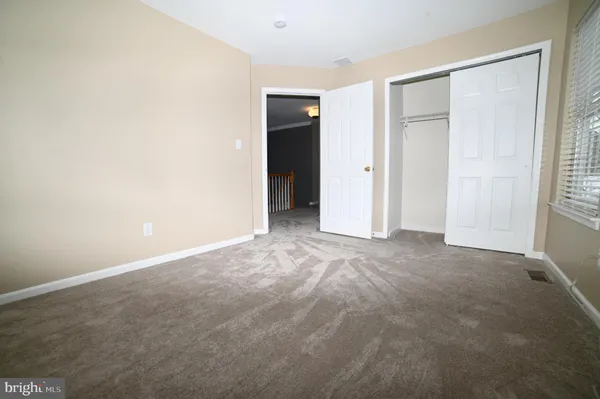 a view of an empty room with closet and a window