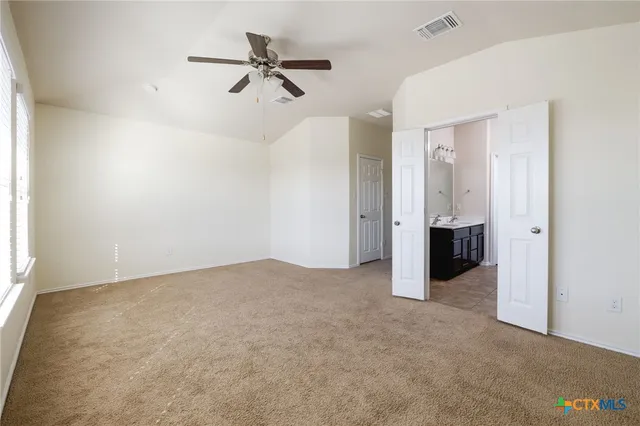 an empty room with closet and a ceiling fan