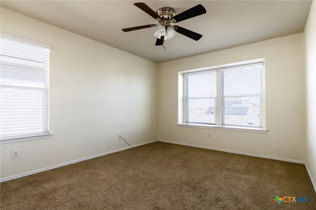 an empty room with a window and a fan