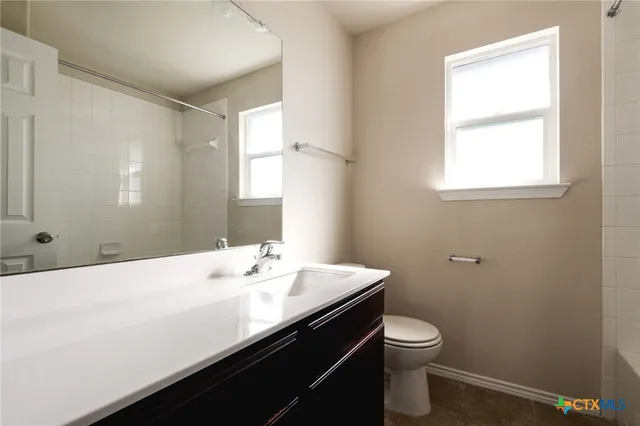 a bathroom with a sink a toilet and a window