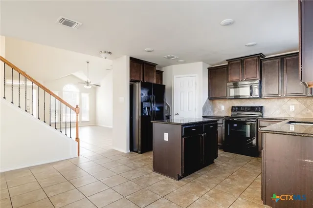 a kitchen with stainless steel appliances granite countertop a refrigerator and a stove