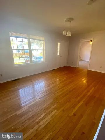 an empty room with wooden floor mirror and windows
