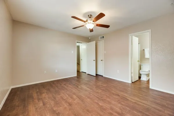 an empty room with wooden floor and ceiling fan