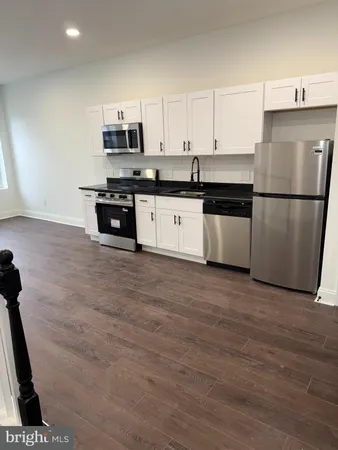a kitchen with granite countertop a refrigerator and a stove top oven