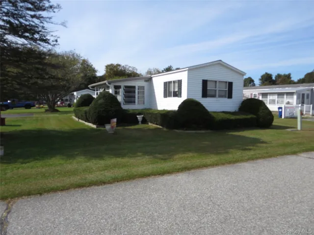 a front view of a house with a garden and trees
