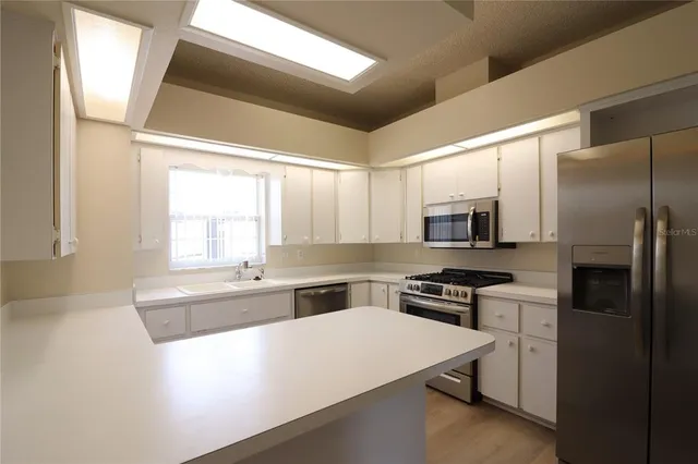 a kitchen with stainless steel appliances a sink a stove a refrigerator and cabinets