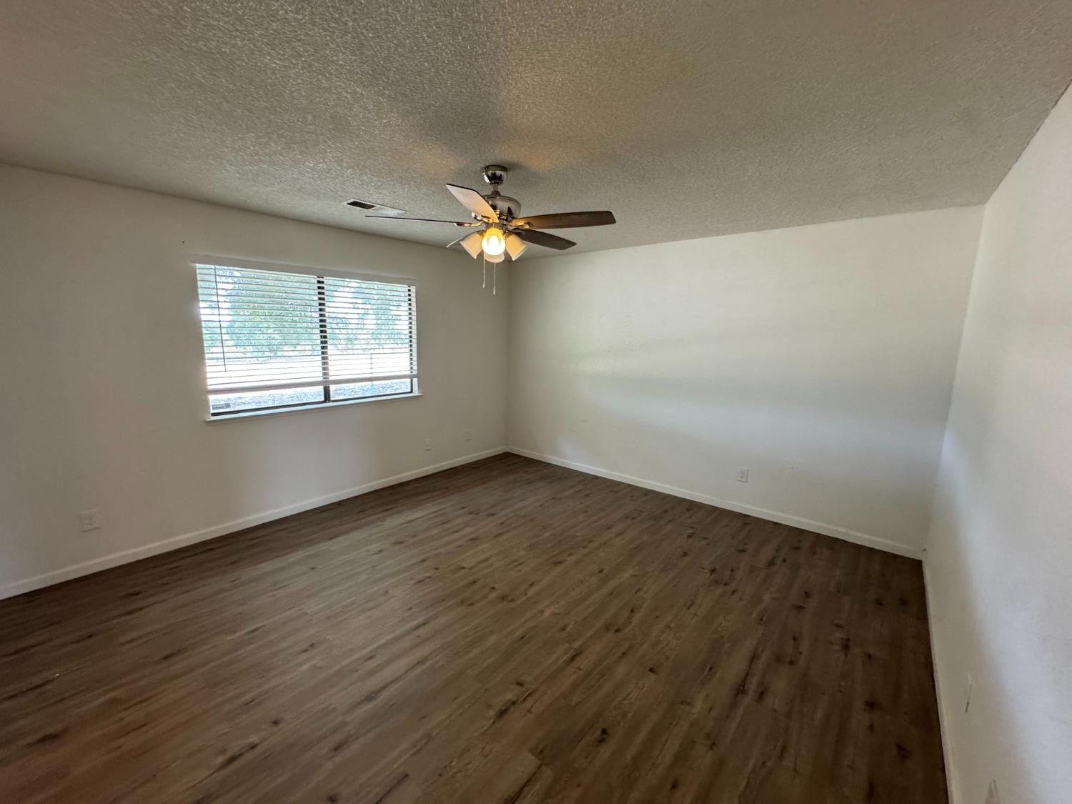 21293 East American Avenue Reedley, CA 93654 - Photo 5 of 19 an empty room with wooden floor fan and windows