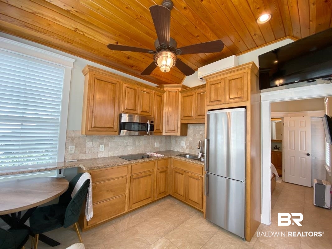 28888 Canal Road, Unit 71 Orange Beach, AL 36561 - Photo 4 of 9 Kitchen with sink, wood ceiling, stainless steel appliances, light stone counters, and tasteful backsplash