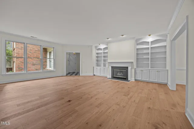a view of empty room with wooden floor and fireplace