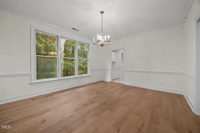 a view of an empty room with window and hardwood floor