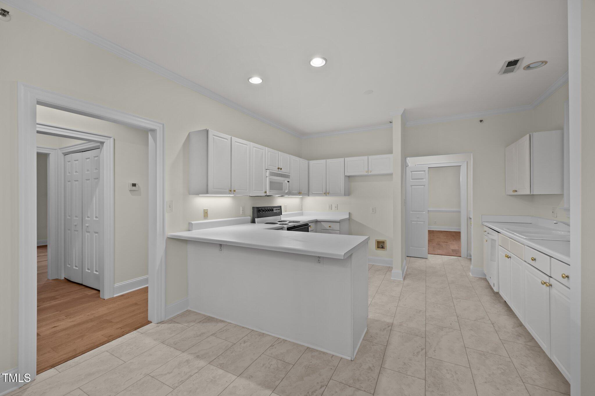 100 Edenburgh Road, Unit 202 Raleigh, NC 27608 - Photo 35 of 52 a large white kitchen with stainless steel appliances granite countertop a sink and cabinets