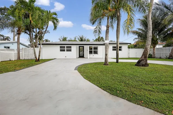 front view of house with a yard and palm trees