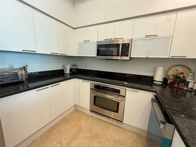 a kitchen with stainless steel appliances granite countertop white cabinets a stove a microwave and a refrigerator