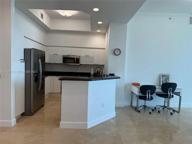 a kitchen with a refrigerator and table chairs