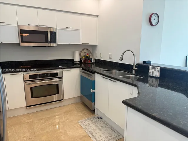 a kitchen with granite countertop a stove top oven microwave and cabinets