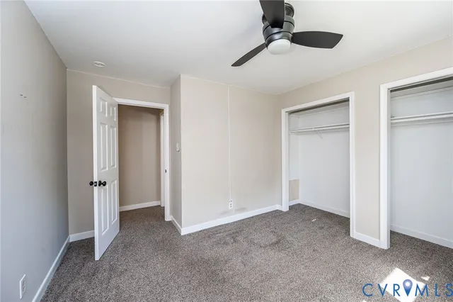 an empty room with a ceiling fan and carpet