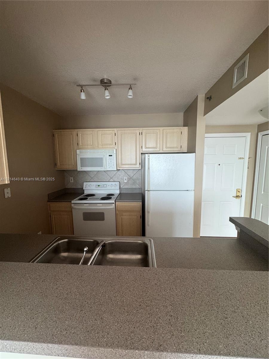 2665 Southwest 37th Avenue, Unit 601 Miami, FL 33133 - Photo 5 of 7 a kitchen with a refrigerator a sink and cabinets