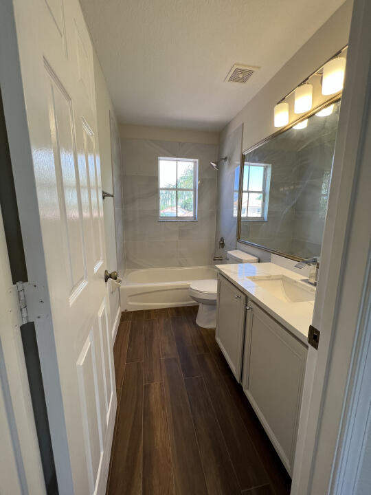 6610 Windmill Way Greenacres, FL 33413 - Photo 18 of 40 a bathroom with a sink a bathtub a toilet and a window