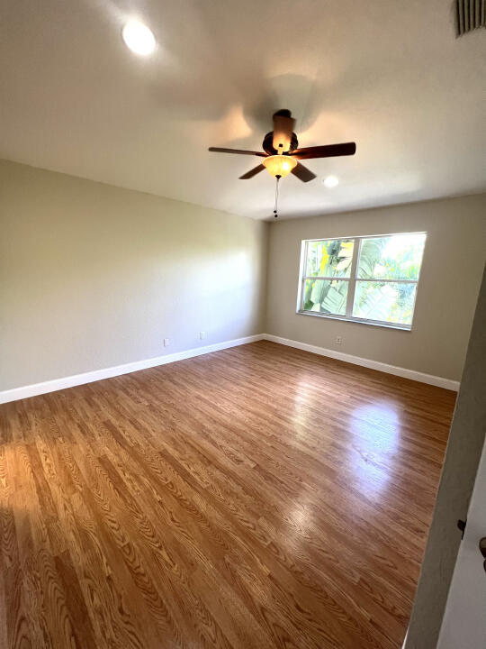 6610 Windmill Way Greenacres, FL 33413 - Photo 20 of 40 an empty room with wooden floor fan and windows