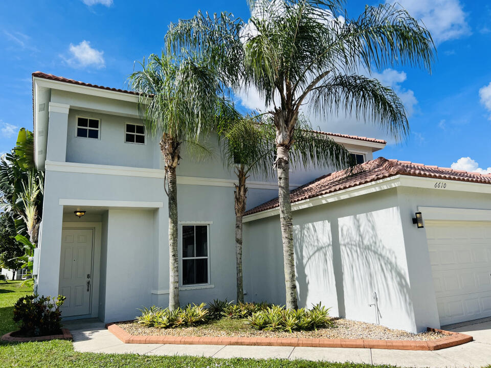 6610 Windmill Way Greenacres, FL 33413 - Photo 2 of 40 a front view of a house with garden