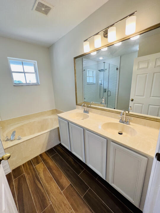 6610 Windmill Way Greenacres, FL 33413 - Photo 25 of 40 a bathroom with a double vanity sink a mirror and a bathtub