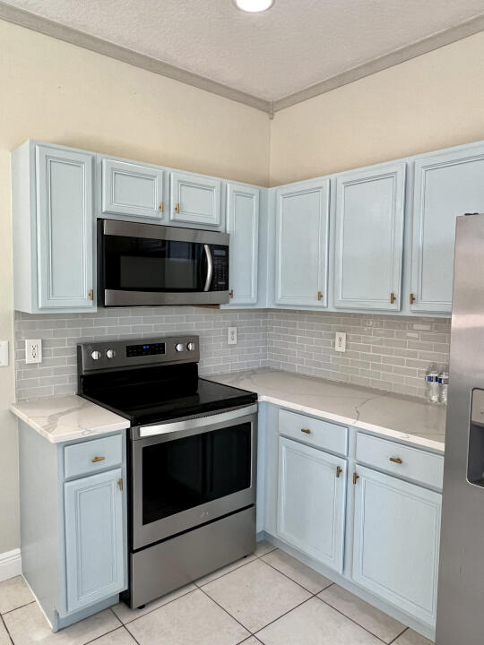 6610 Windmill Way Greenacres, FL 33413 - Photo 8 of 40 a kitchen with white cabinets and stainless steel appliances