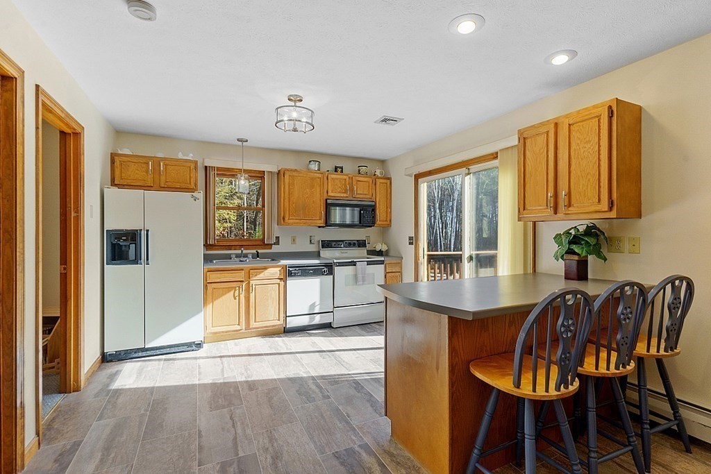 169 Wallace Hill Road Townsend, MA 01469 - Photo 27 of 42 a kitchen with stainless steel appliances granite countertop a stove top oven a sink dishwasher a dining table and chairs with wooden floor